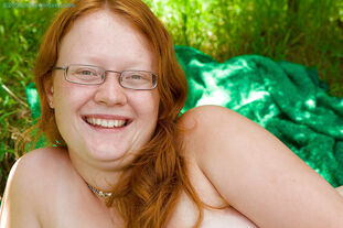 Gross red-haired damsel in glasses peels off nude outdoors