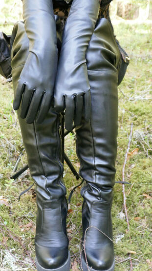 Clad woman wears leather gloves and footwear plus shades in