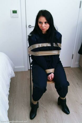 Dark-haired police doll finds herself taped to a stool in