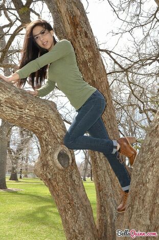 Latina woman Bella Quinn climbs a tree in the park wearing a