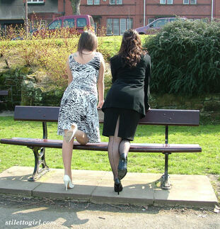 Clad females admire each other high heeled boots on a park